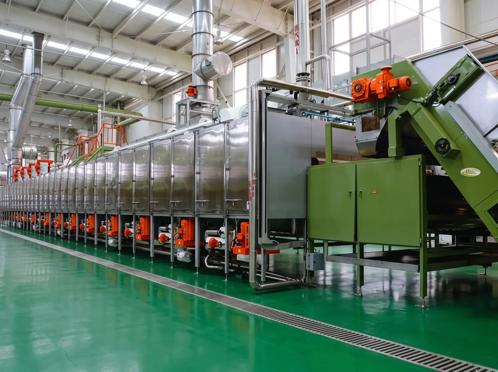 A long stainless-steel leaf conditioning and drying line on a clean factory floor